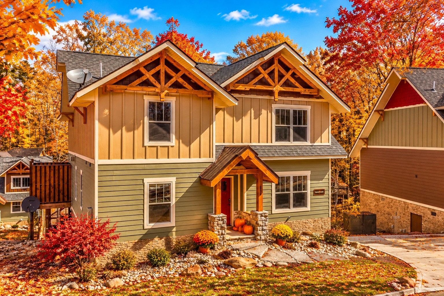 A two-story house with a stone foundation, a red door, and a porch with a stone railing.