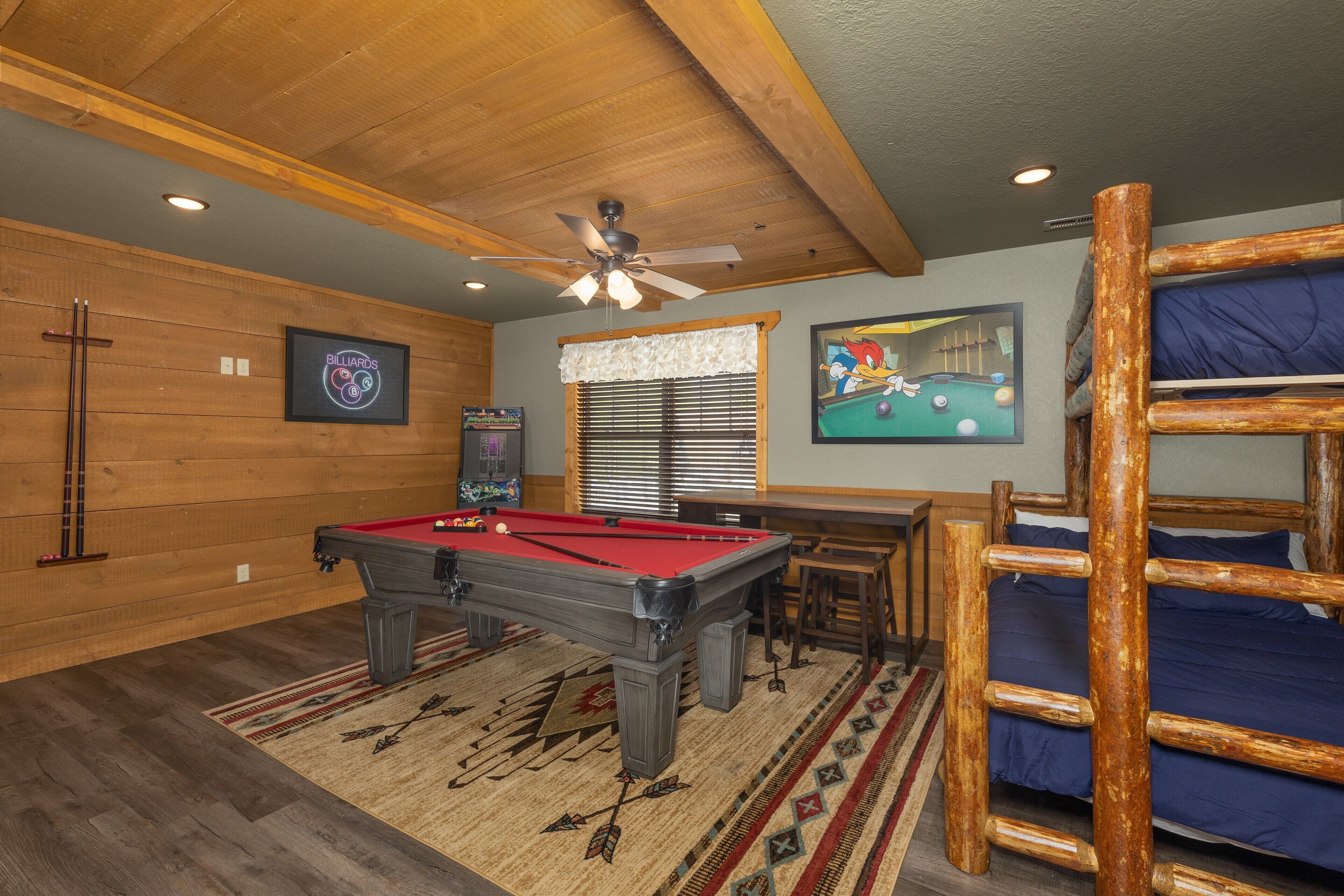 A pool table in a room with wooden walls and a ceiling fan.