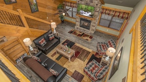 A spacious living room with a stone fireplace, wooden ceiling beams, and a large TV. - Bearvue Point (Gatlinburg)