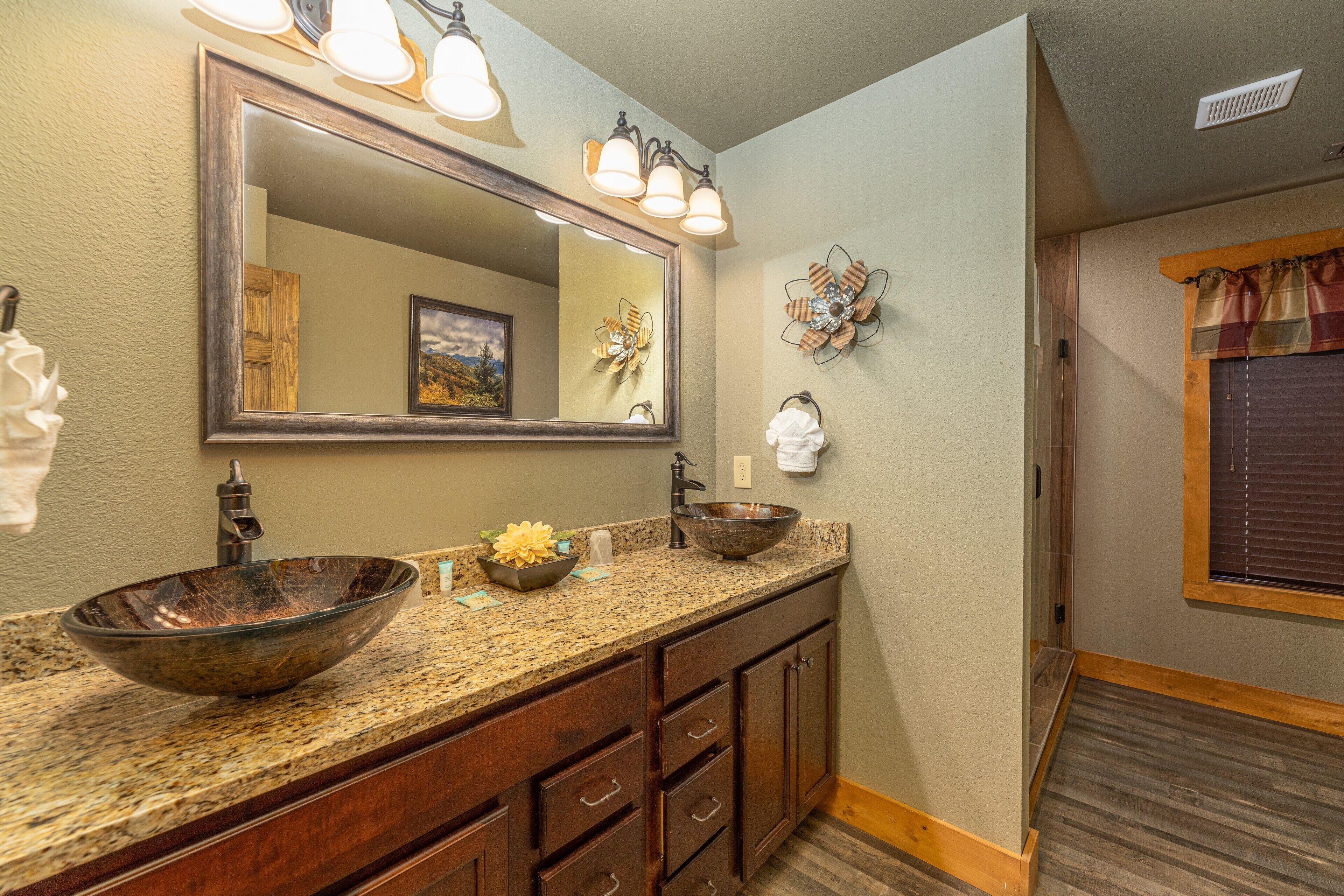 A bathroom with a large mirror, a vessel sink, and wooden cabinetry.