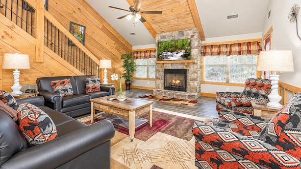 A spacious living room with a fireplace, leather sofas, and a wooden staircase. - Bearvue Point (Gatlinburg)