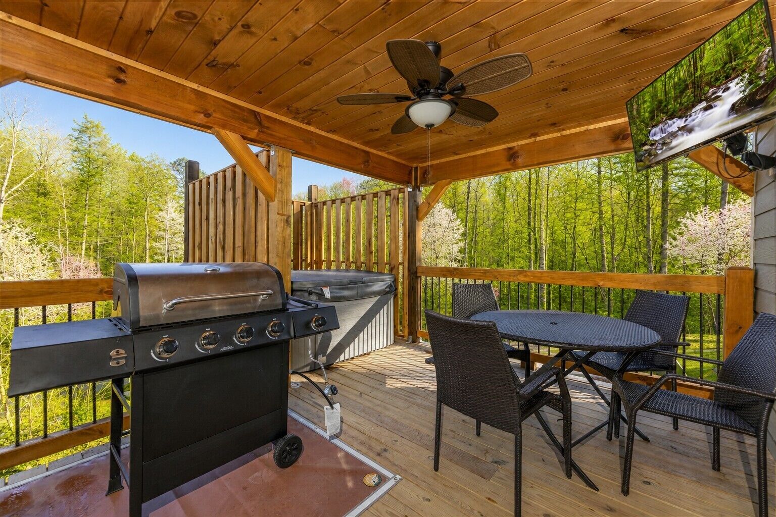 An outdoor deck with a grill, chairs, and a table.