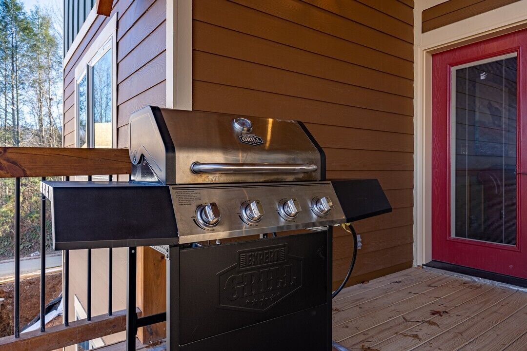 Un barbecue en acier inoxydable doté de quatre brûleurs et d’un brûleur latéral, installé sur une terrasse en bois.