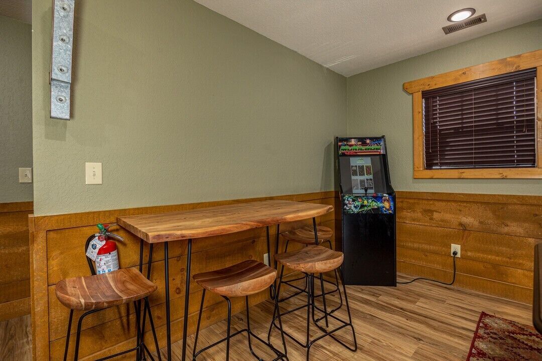 Eine Bar mit Holztresen, Hockstühlen, einem Feuerlöscher und einem Kühlschrank.