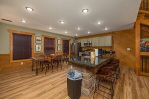 A spacious kitchen with a central island, wooden flooring, and built-in appliances. - Luna Bear Lodge (Gatlinburg)