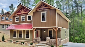 A two-story house with a porch, stone pillars, and a red awning. - Head Over Hills (Gatlinburg)