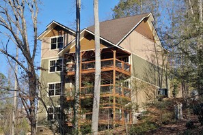 A multi-story house with a balcony on the second floor, surrounded by trees. - Splash Time Cinema (Gatlinburg)