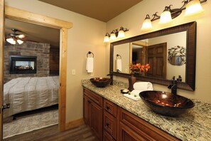 A bathroom with a large mirror, a vessel sink, and a wooden vanity. - Splash Time Cinema (Gatlinburg)