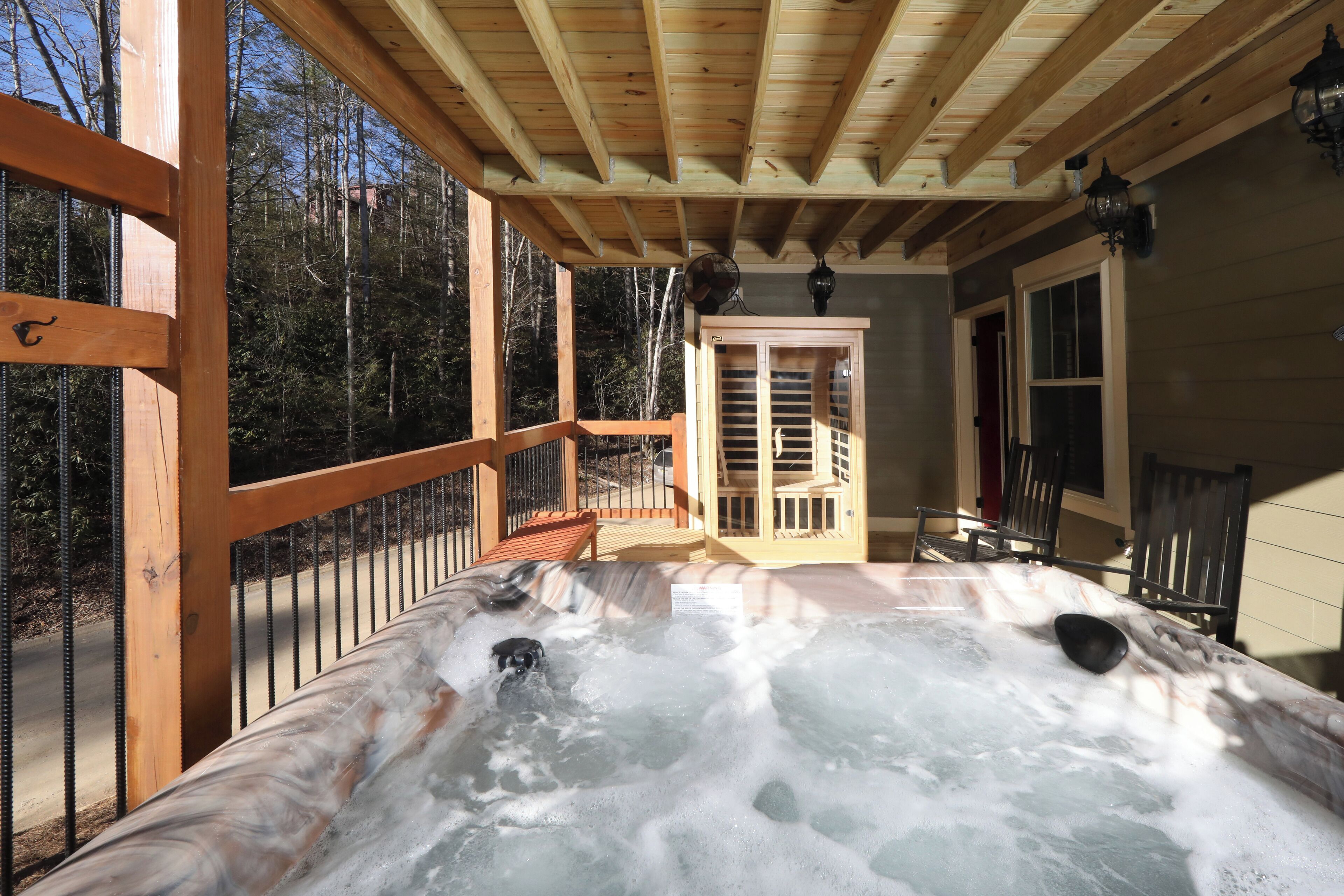 A hot tub with a wooden deck and a view of the forest.