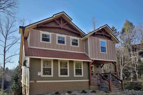 A two-story house with a brown roof, beige siding, and a stone staircase leading to a porch. - Splash Time Cinema (Gatlinburg)