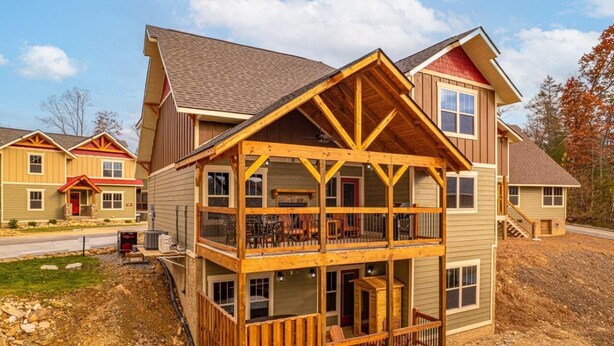 A two-story wooden cabin with a balcony, a front porch, and a garage. - A Time for Us (Gatlinburg)