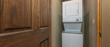 A laundry room with a white washer and dryer, wooden cabinets, and a textured wall.