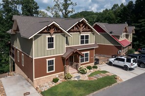 A two-story house with a front porch, stone foundation, and a driveway. - Running Bear (Gatlinburg)