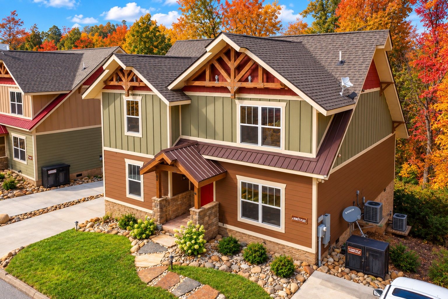 A two-story residential building with a stone foundation, a covered front porch, and a satellite dish on the roof.