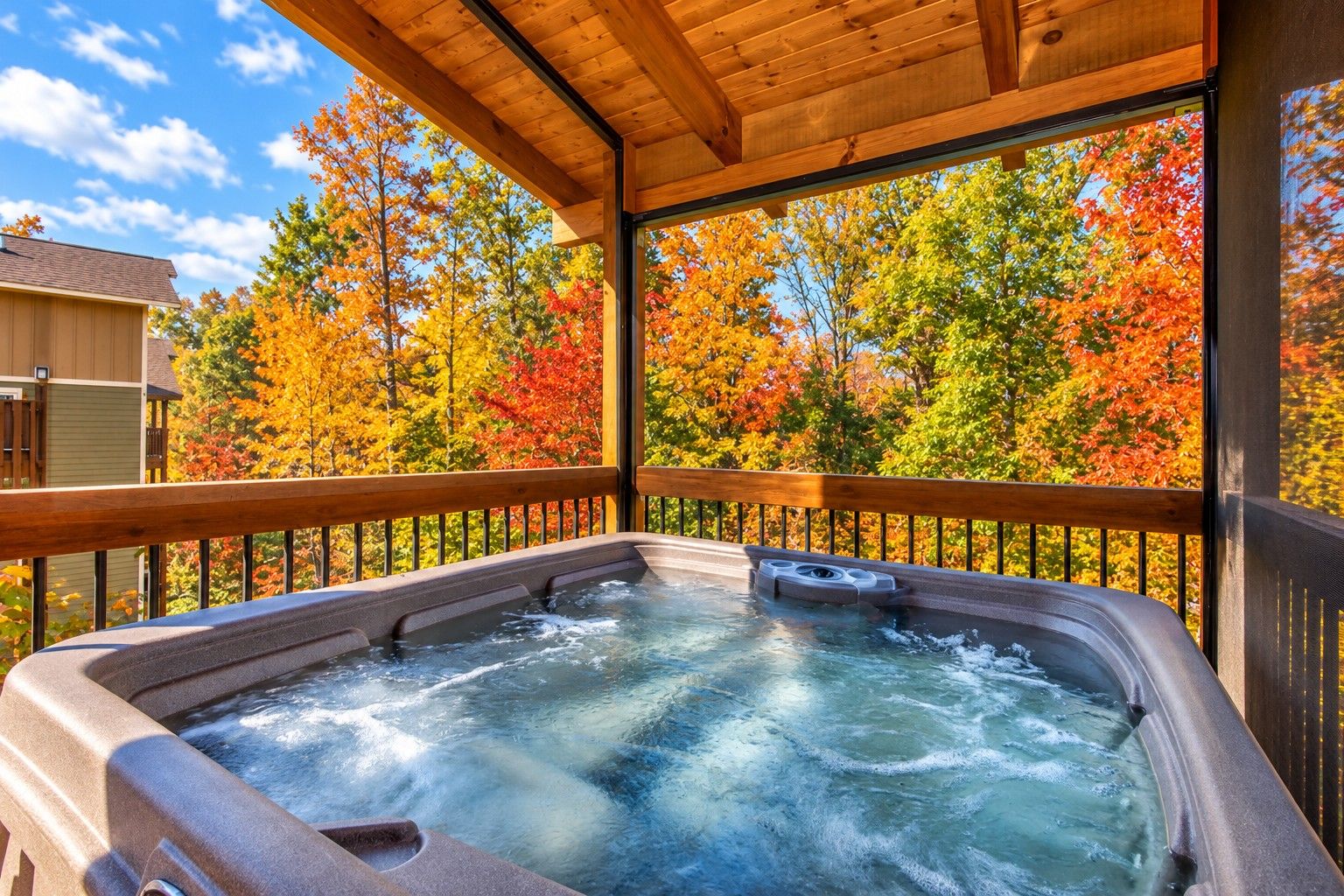 A hot tub with a wooden deck and a view of autumn trees.