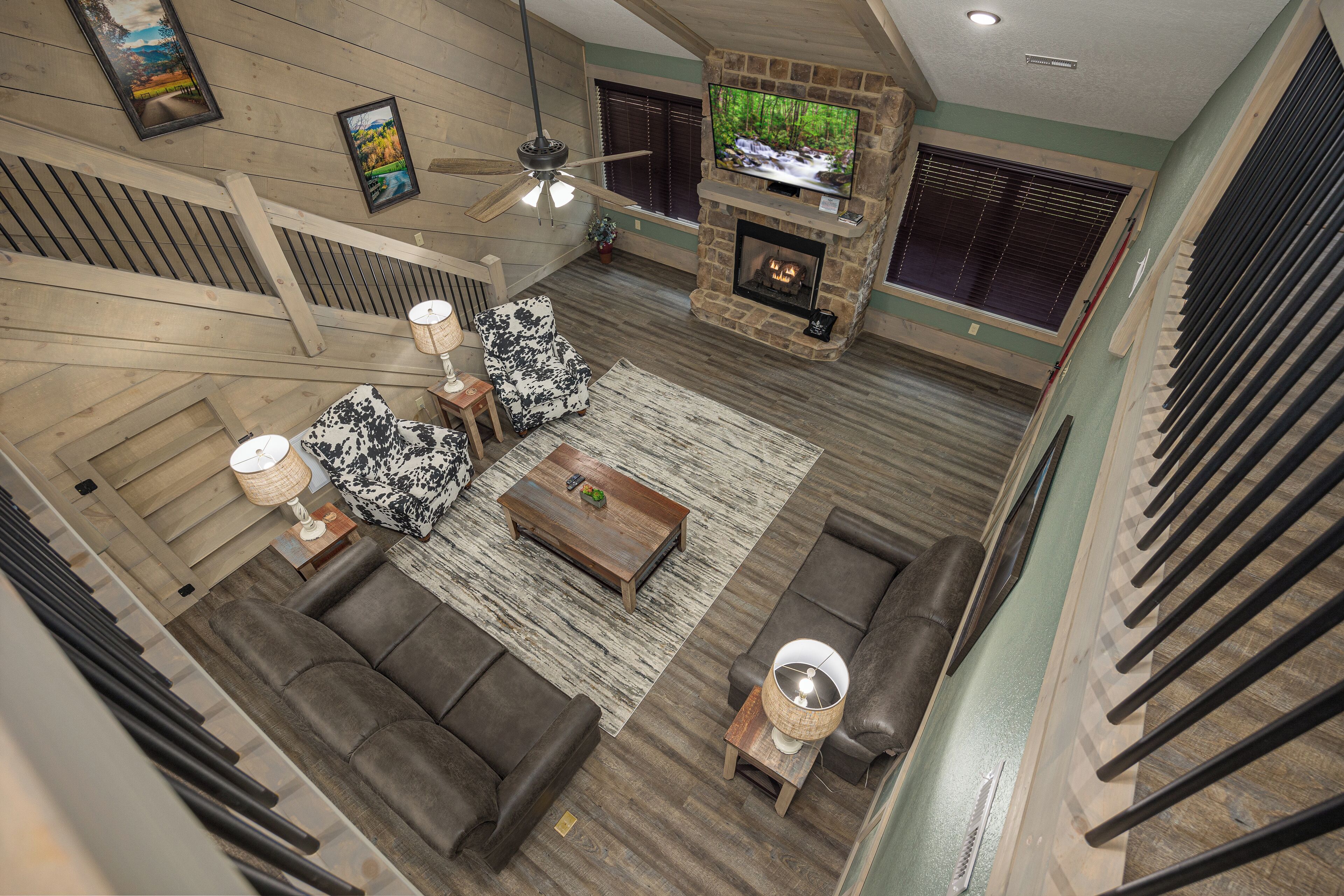 A spacious living room with a fireplace, a large TV, and a ceiling fan.