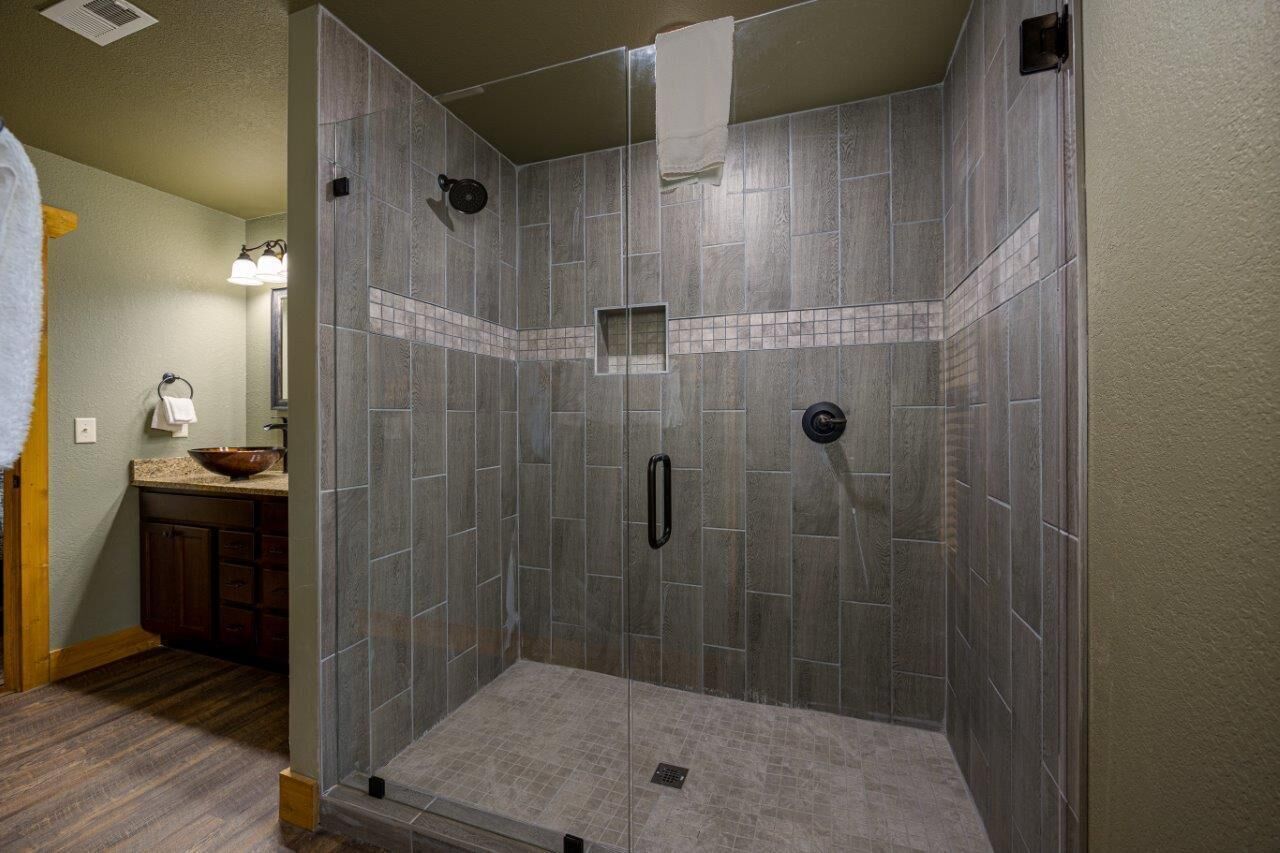 Una ducha a ras de suelo con suelo y paredes de azulejos, un cabezal de ducha manual y una ventana pequeña.
