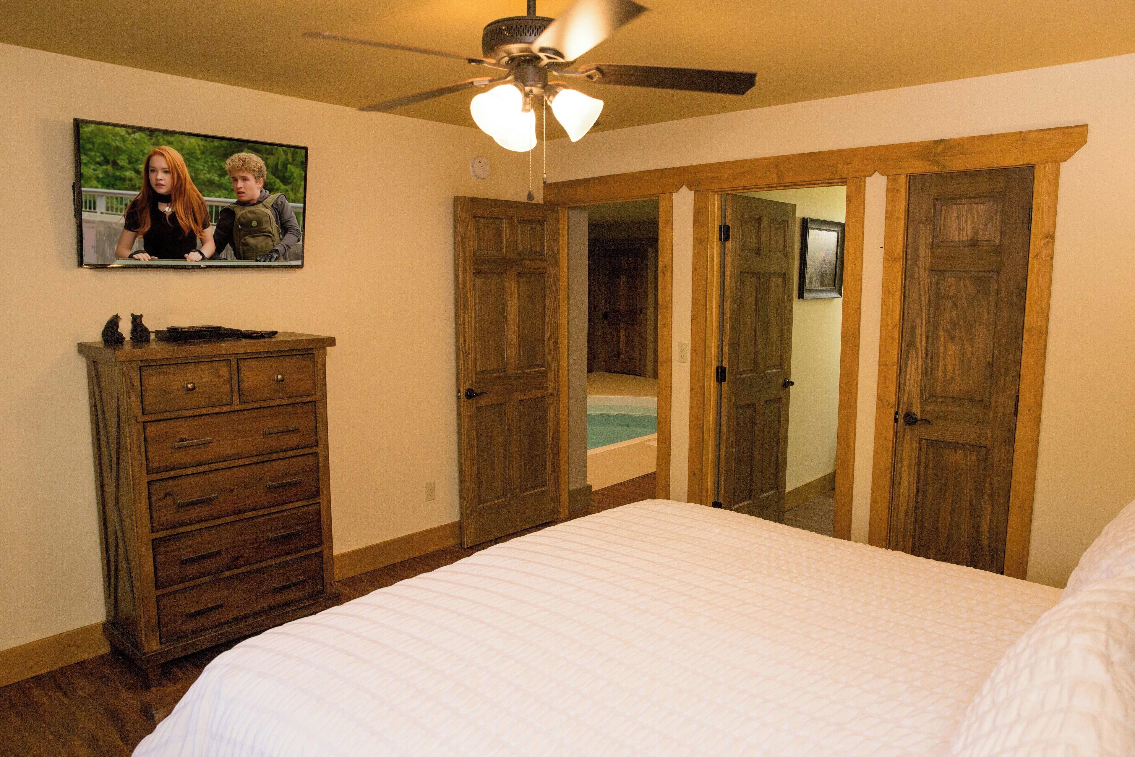 Ein Schlafzimmer mit einem Bett, einer Holzkommode und einem Deckenventilator.