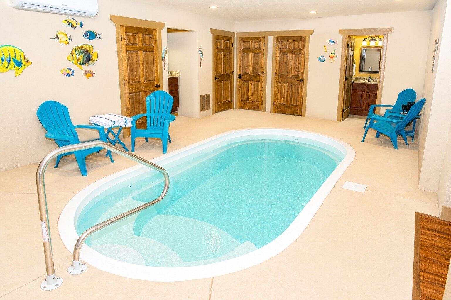 En swimmingpool med blå stolar, trädörrar och fiskmotiv på väggen.