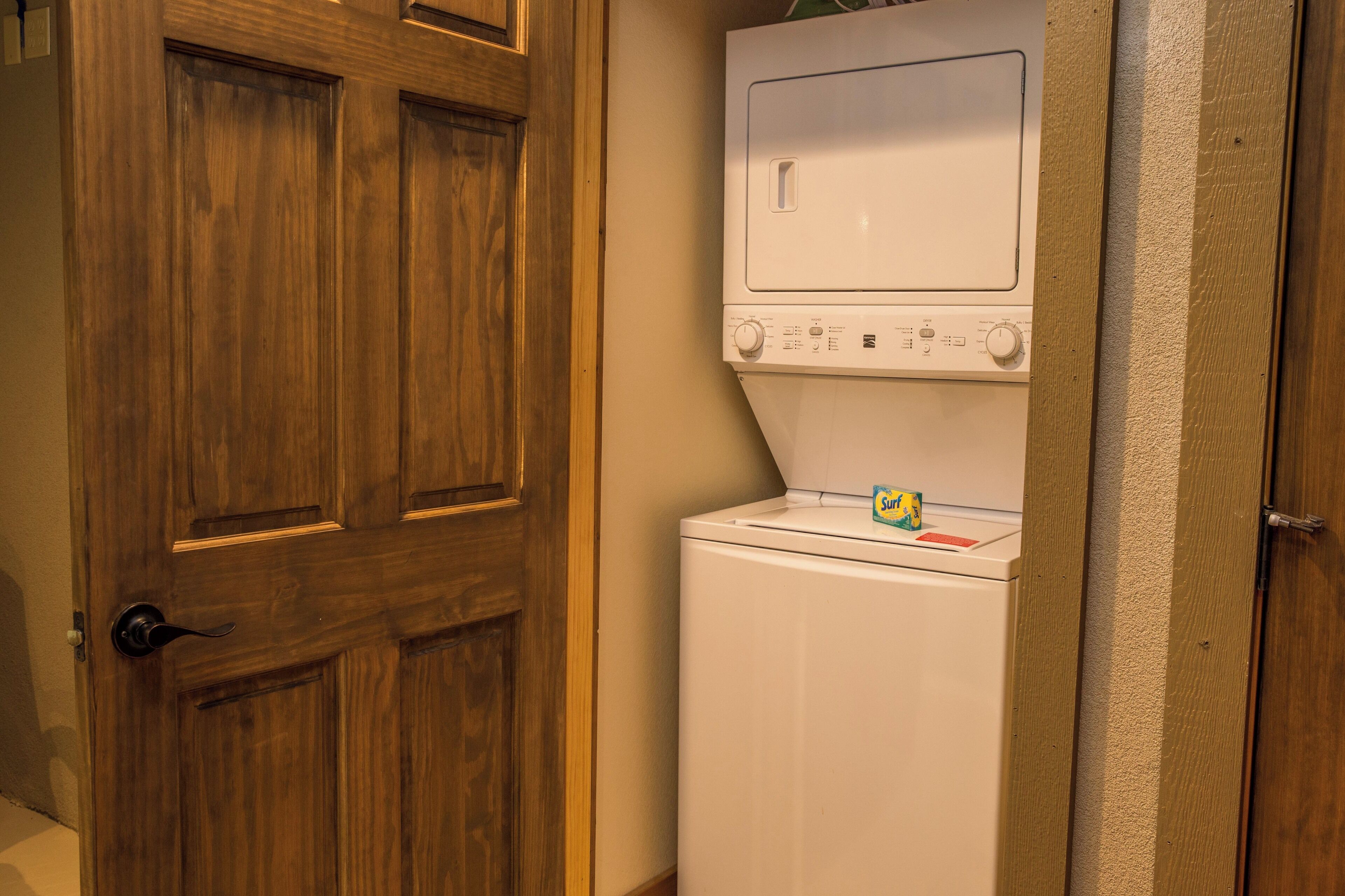 A laundry room with a wooden door and a white washer and dryer.