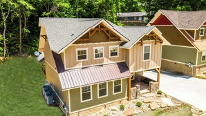 Una casa a più piani in legno con tetto spiovente, diverse finestre e un'antenna parabolica.