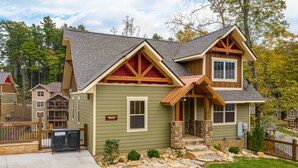 A two-story house with a stone foundation, a sloped roof, and a front porch. - Moonshine Manor (Gatlinburg)