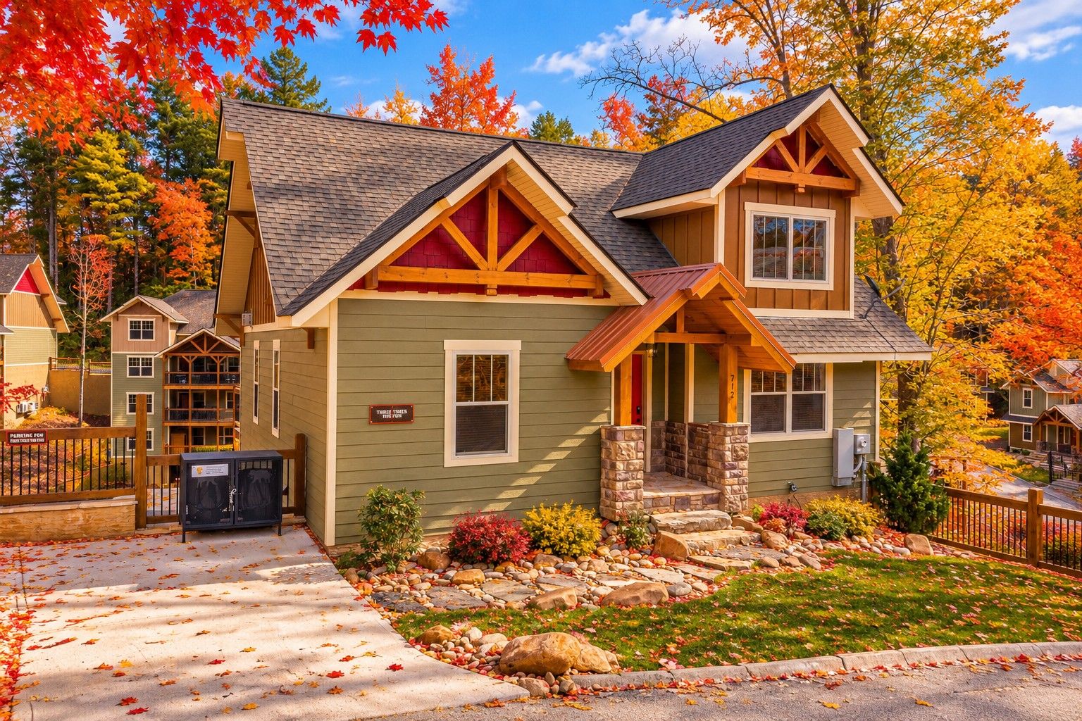 A two-story house with a stone foundation, a front porch, and a driveway leading to a parking area.