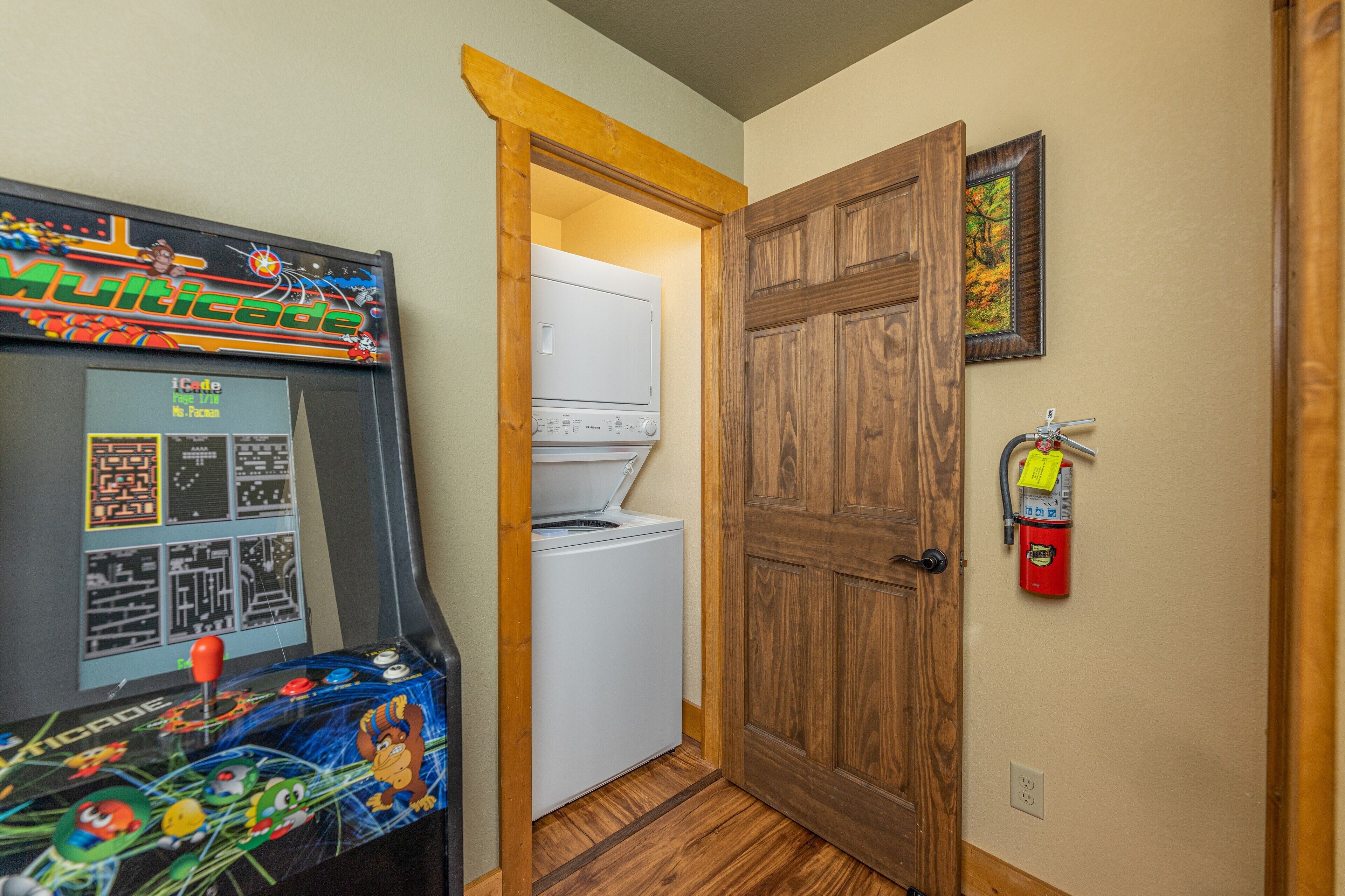 A room with a washing machine, a wooden door, and a fire extinguisher on the wall.