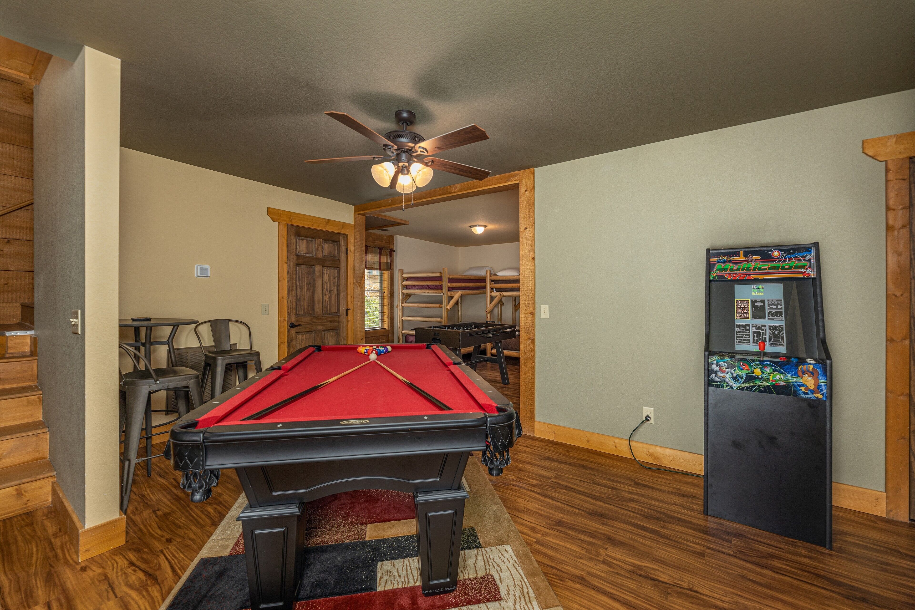 A pool table in a room with wooden floors and a ceiling fan.
