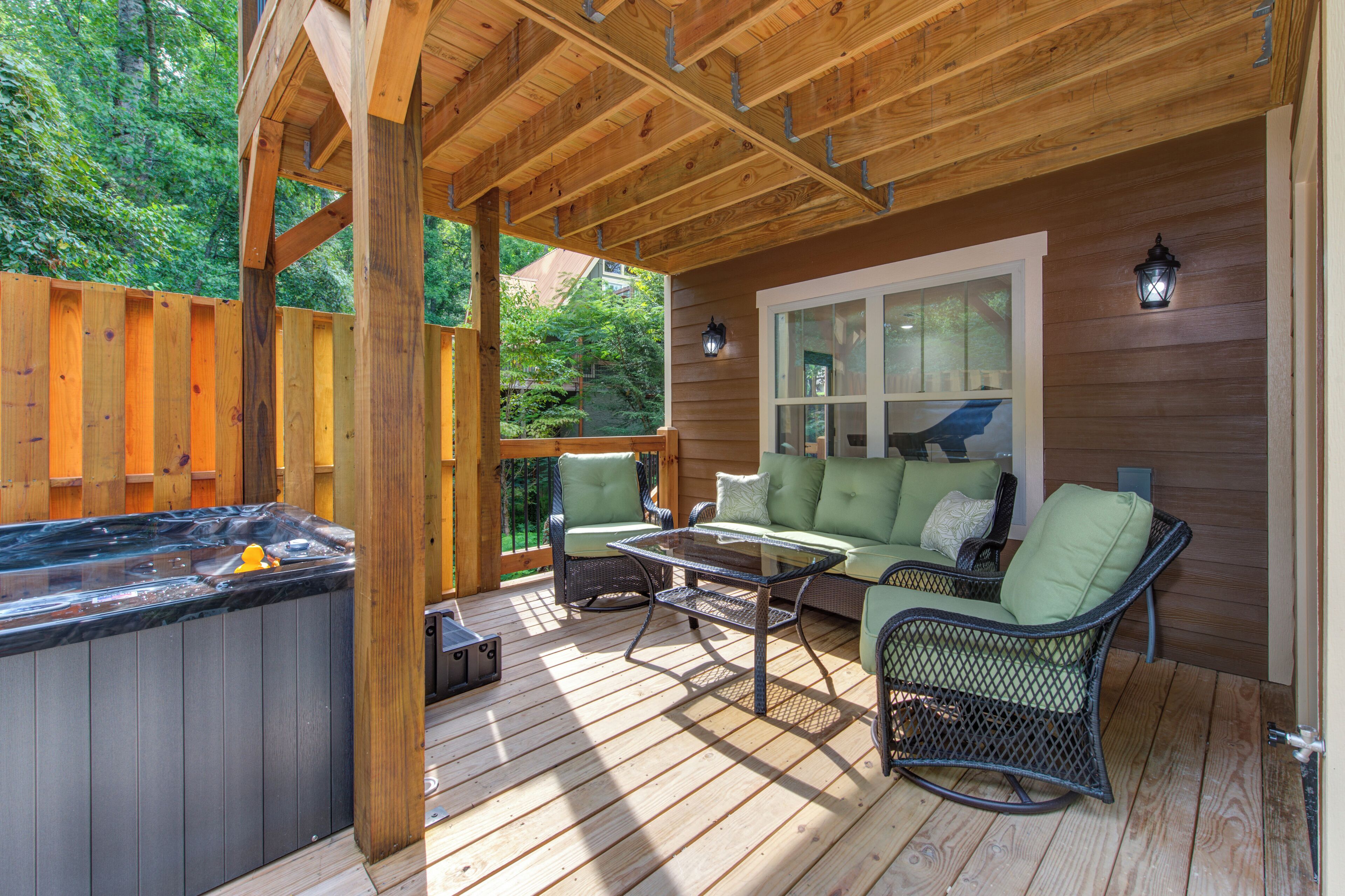 An outdoor deck with a hot tub, seating area, and a wooden pergola.