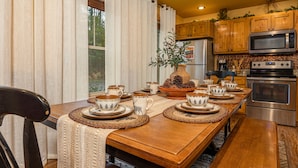Comedor con mesa de madera dispuesta para cuatro personas, rodeada de sillas.