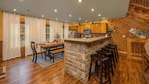 Una cocina con armarios de madera, una isla de piedra y un comedor con mesa y sillas.