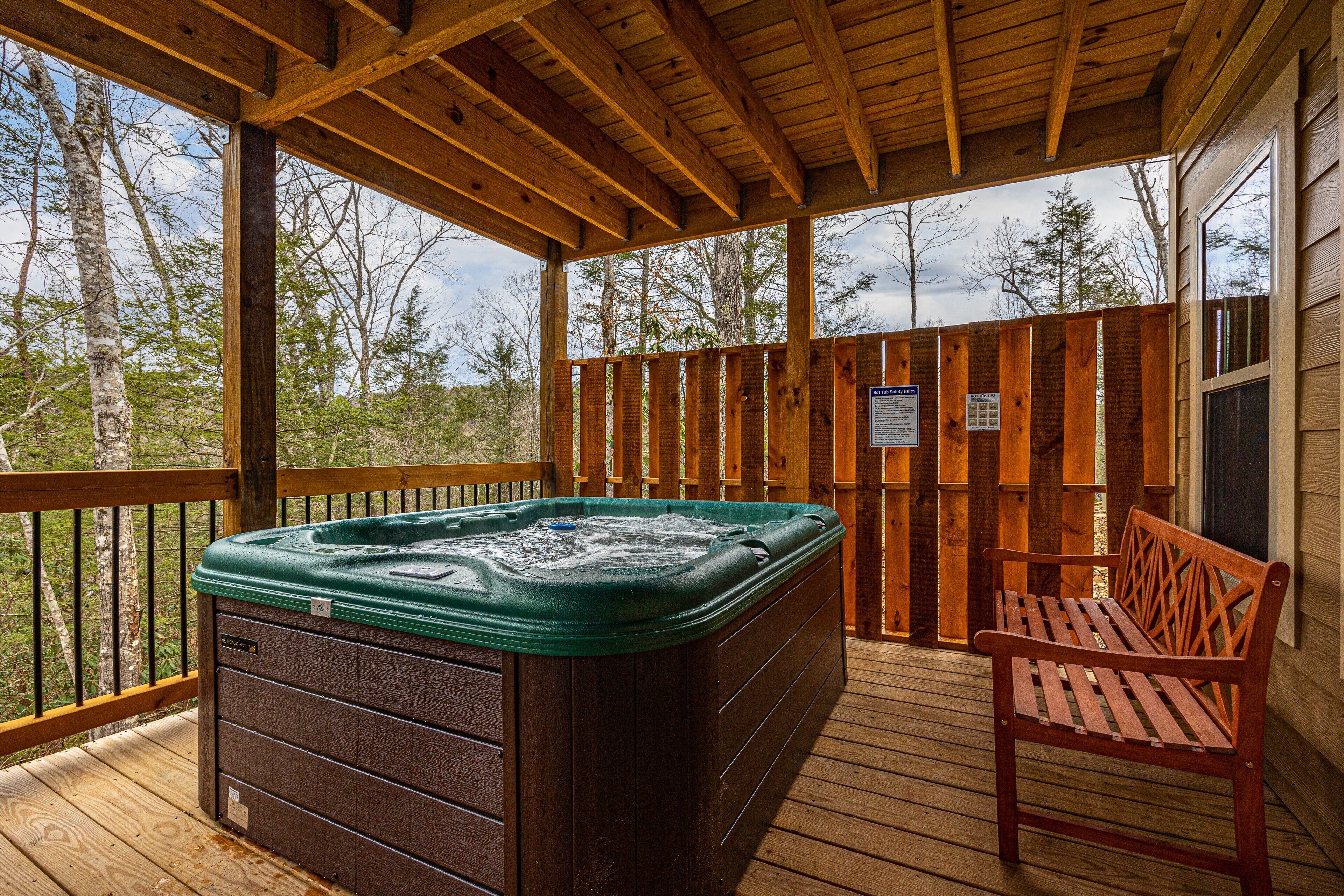 A wooden deck with a hot tub and a wooden bench.