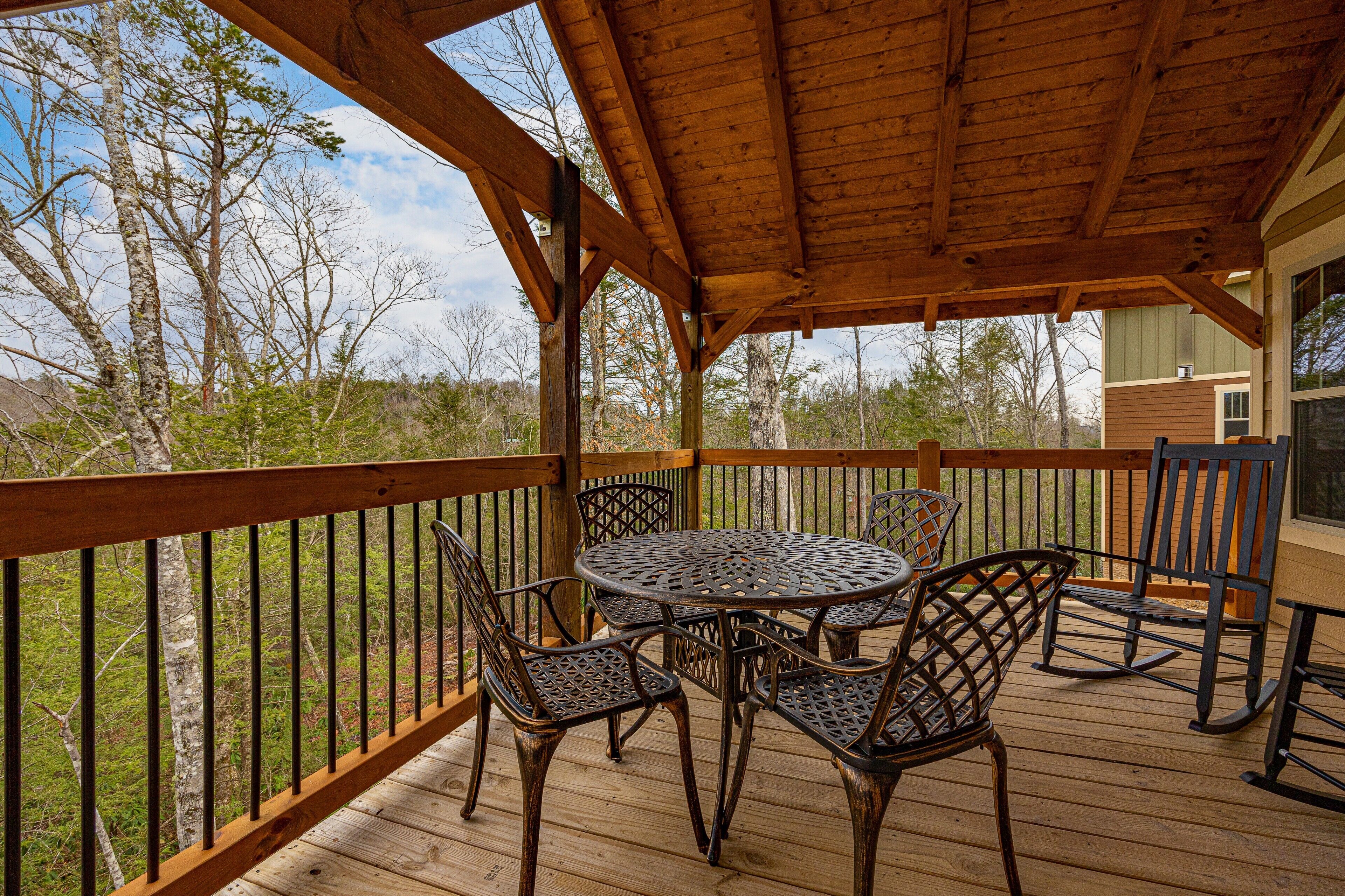 A wooden deck with a round table and chairs, surrounded by a wooden railing.