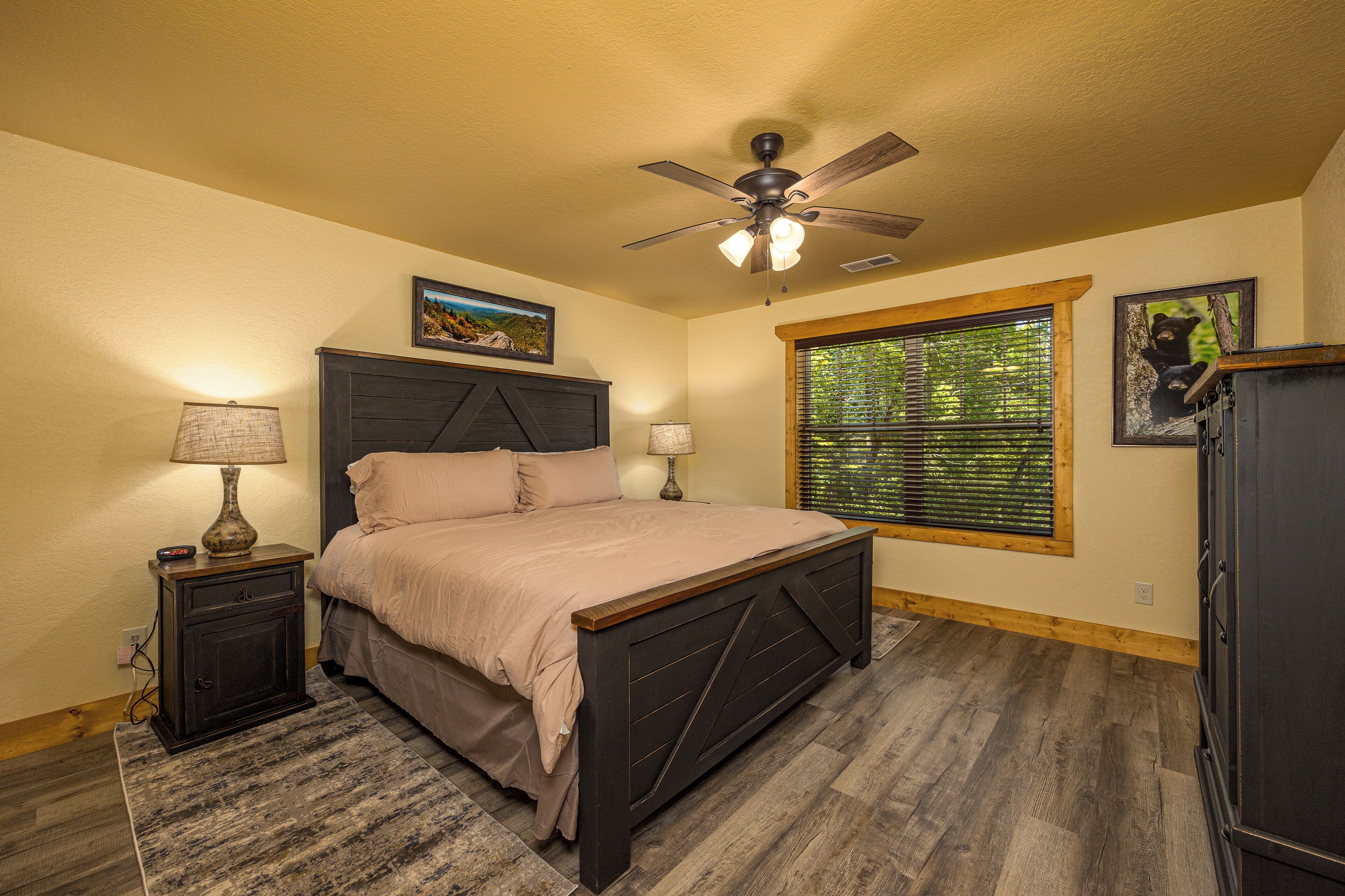 A bedroom with a bed, two bedside tables, a ceiling fan, and a window with blinds.