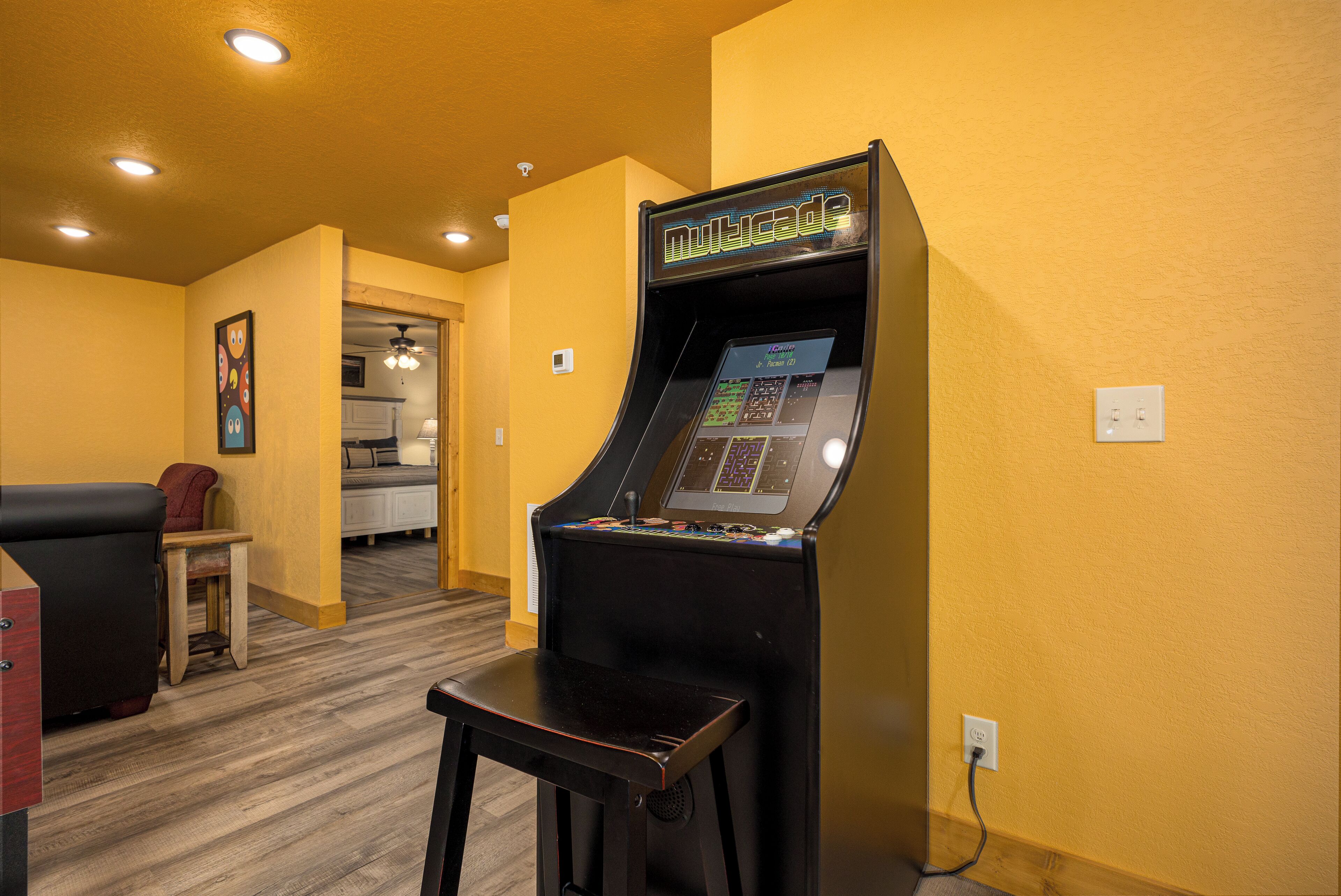 A room with a gaming machine labeled "Multicade," a small table, a chair, and a couch.