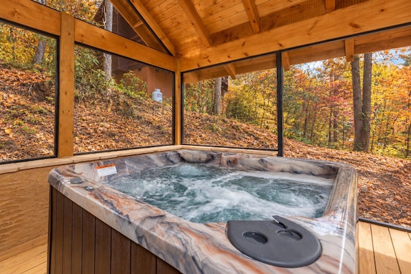 A hot tub with a wooden interior and large windows overlooking a forested area. - Heavenly Haven (Gatlinburg)