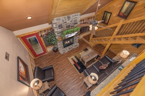 A spacious living area with a stone fireplace, wooden ceiling beams, and a cozy seating arrangement. - Heavenly Haven (Gatlinburg)