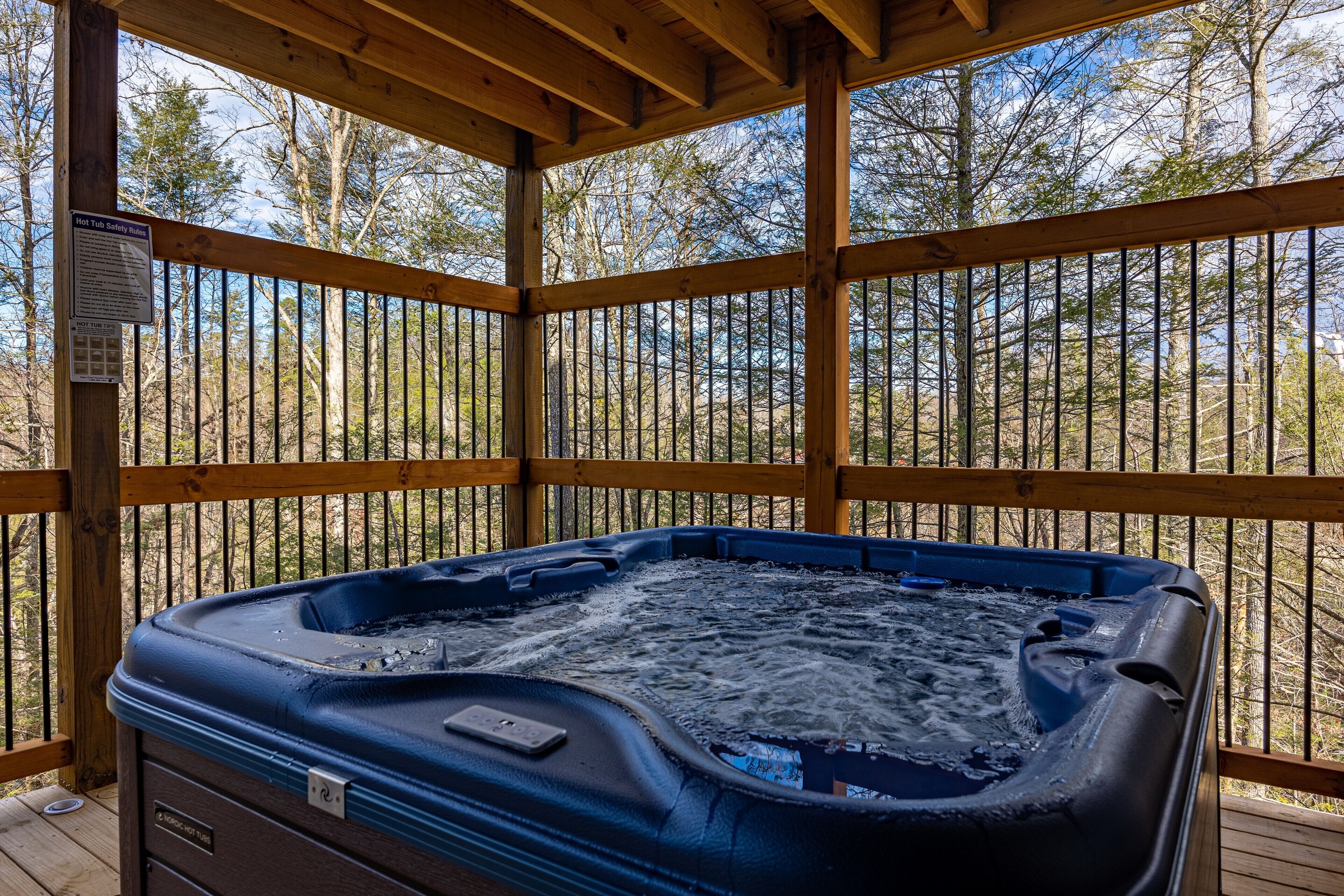 Ein Whirlpool auf einer Holzterrasse mit Blick auf Bäume.