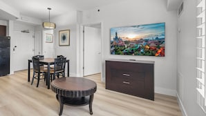 Ein modernes Wohnzimmer mit Essbereich, einem Flachbildfernseher an der Wand und Blick auf eine Stadtansicht.