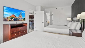 Ein Hotelzimmer mit Bett, Fernseher, Schminktisch und einer Tür zu einem Badezimmer.