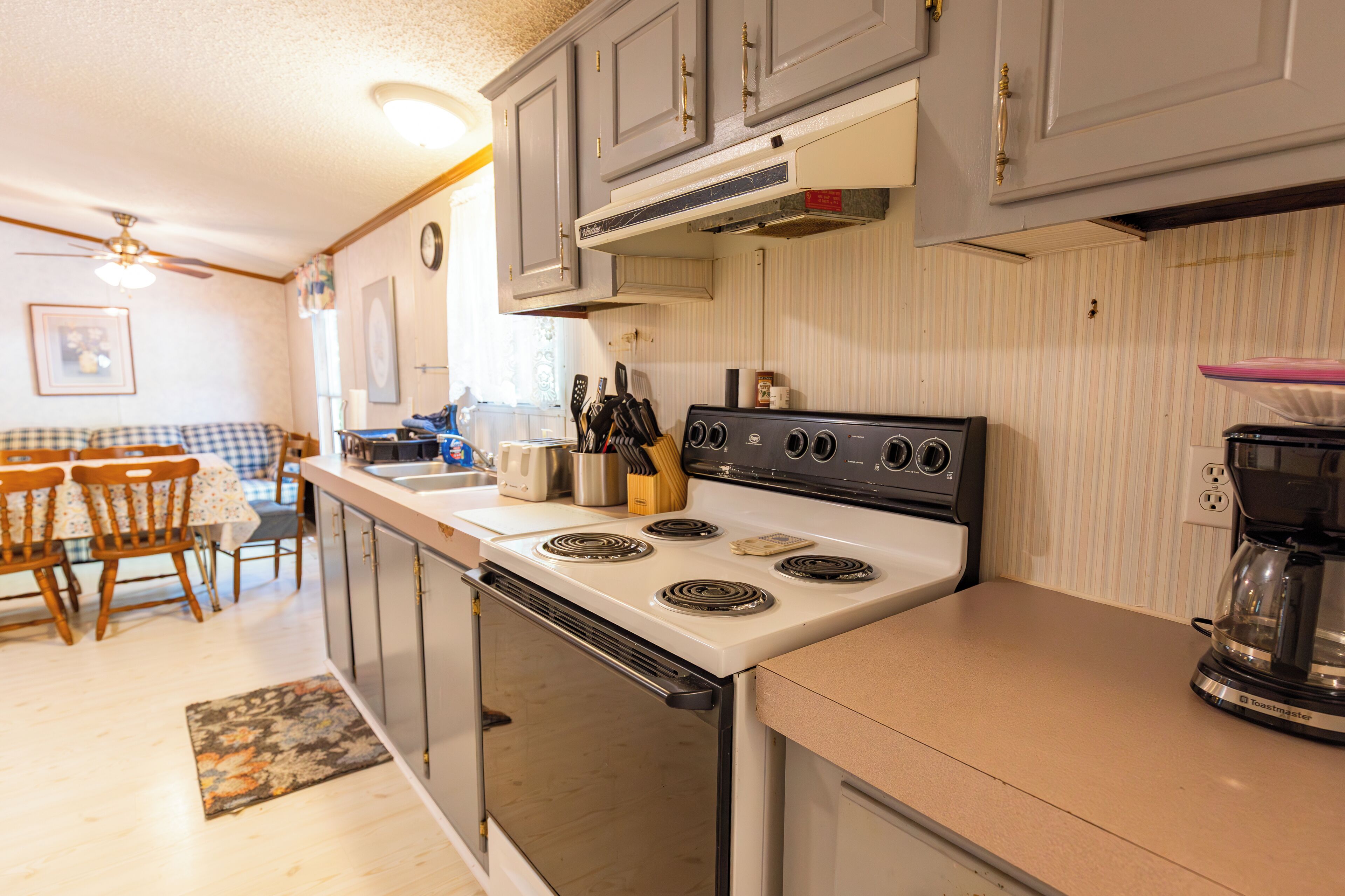 A kitchen with a stove, oven, and dining area with chairs and a table.
