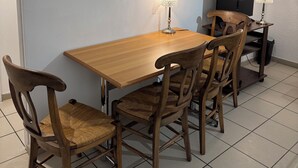 A dining area with a wooden table and chairs, a television, and two table lamps. - Apparently 2 rooms (Vaulx-en-Velin)