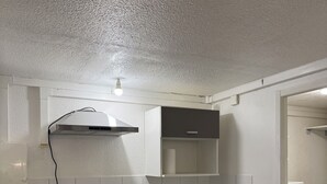A compact kitchen with white cabinets, a built-in stove, a sink, and a small refrigerator. - Apparently 2 rooms (Vaulx-en-Velin)
