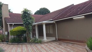 Una casa con techo de tejas, un porche cubierto y un camino de entrada pavimentado.