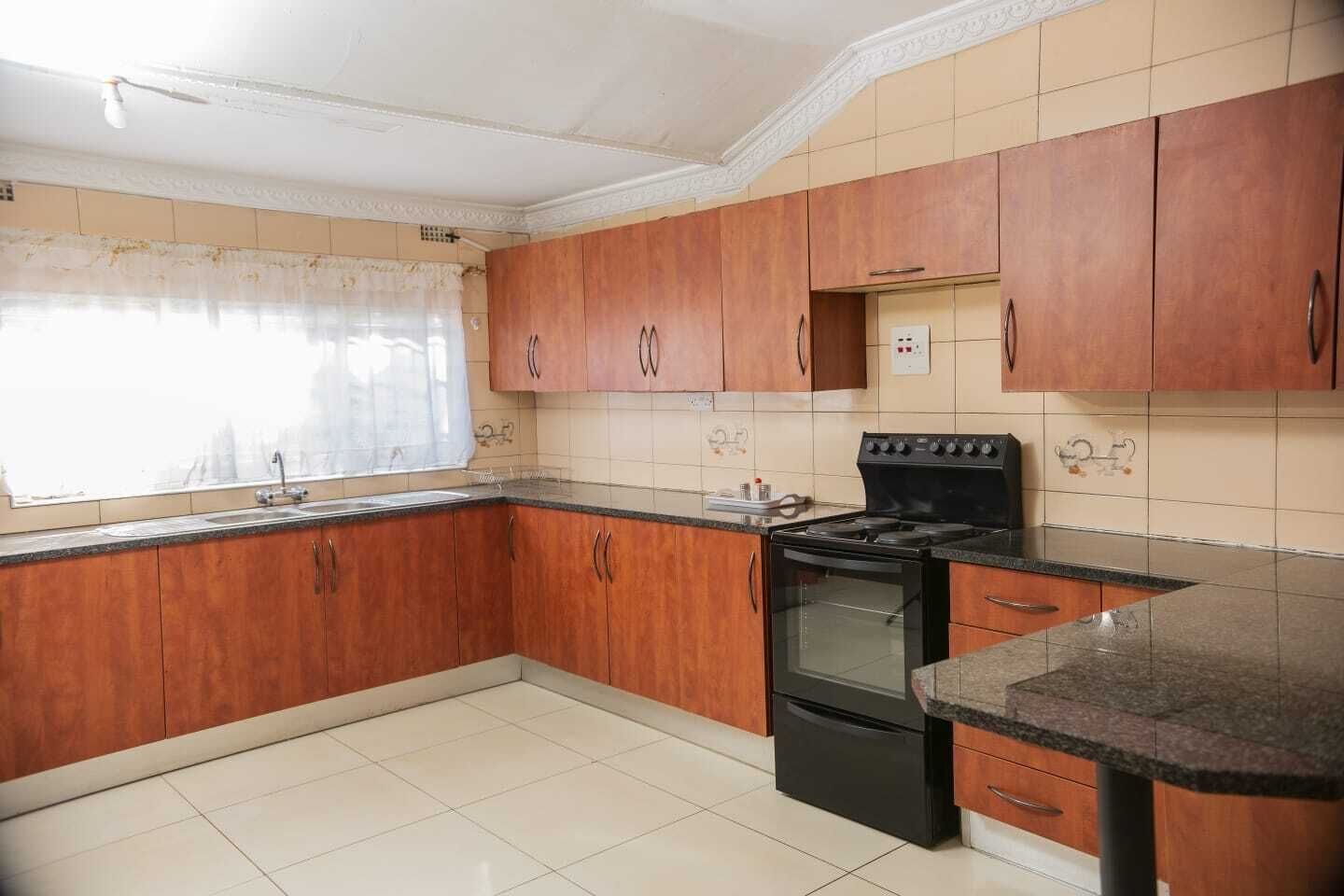 A kitchen with wooden cabinets, a black stove, and a tiled backsplash.