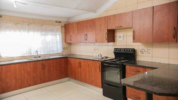 A kitchen with wooden cabinets, a black stove, and a tiled backsplash.