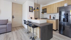Una cocina moderna con una isla central, taburetes de bar, un refrigerador y armarios de madera.