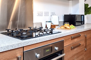 A kitchen with a gas stove, a microwave, and a coffee maker.