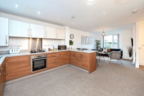 A modern kitchen with wooden cabinets, a built-in oven, and a dining area with a view.